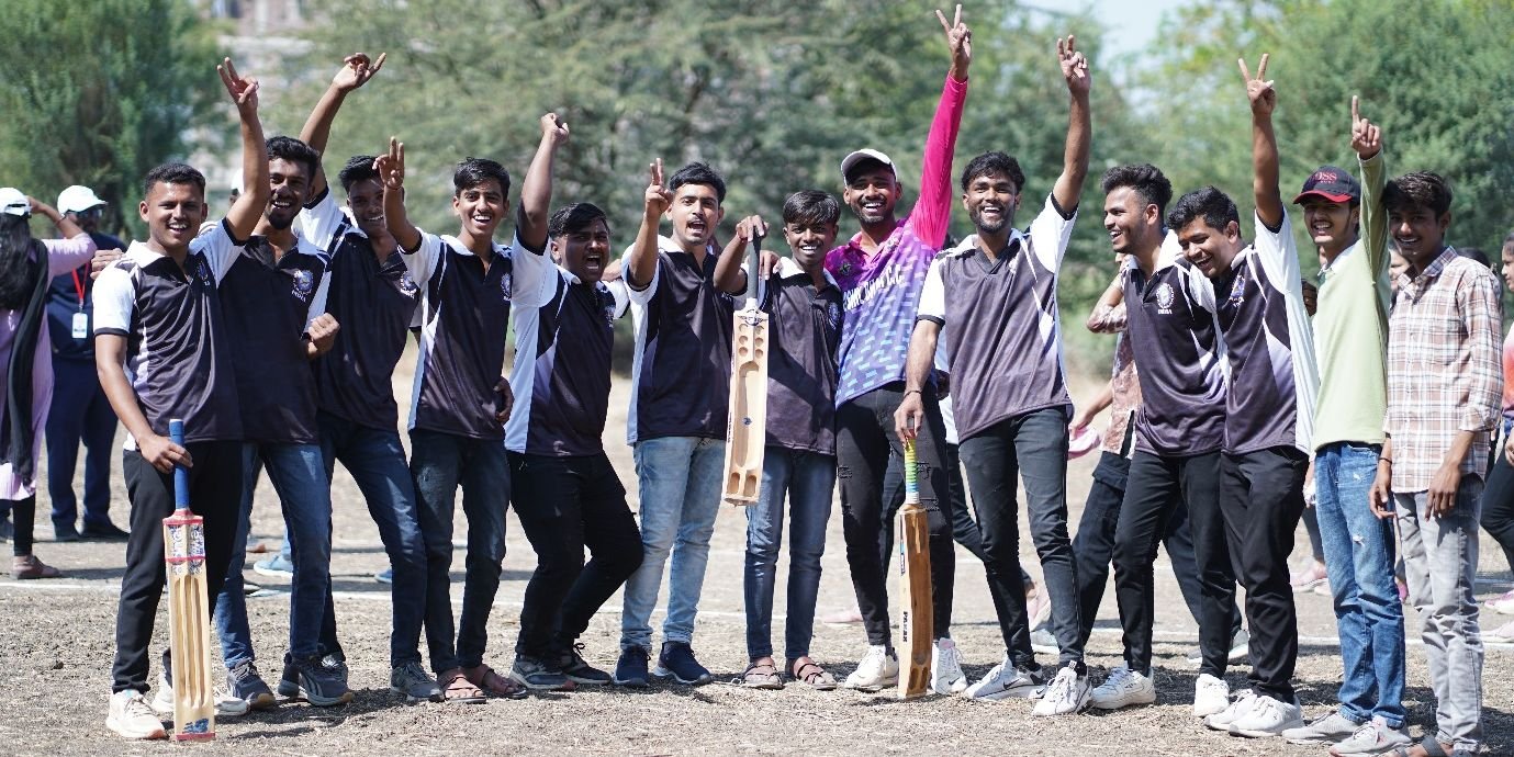 Students with cricket bats celebrating on the ground